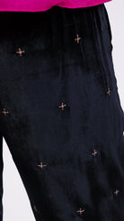 woman wearing VAAI elasticated waist black velvet trouser with gold cross stitch