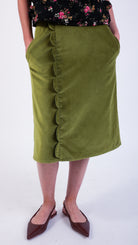 Woman wearing scallop detail green velvet skirt