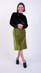 Woman wearing scallop detail green velvet skirt