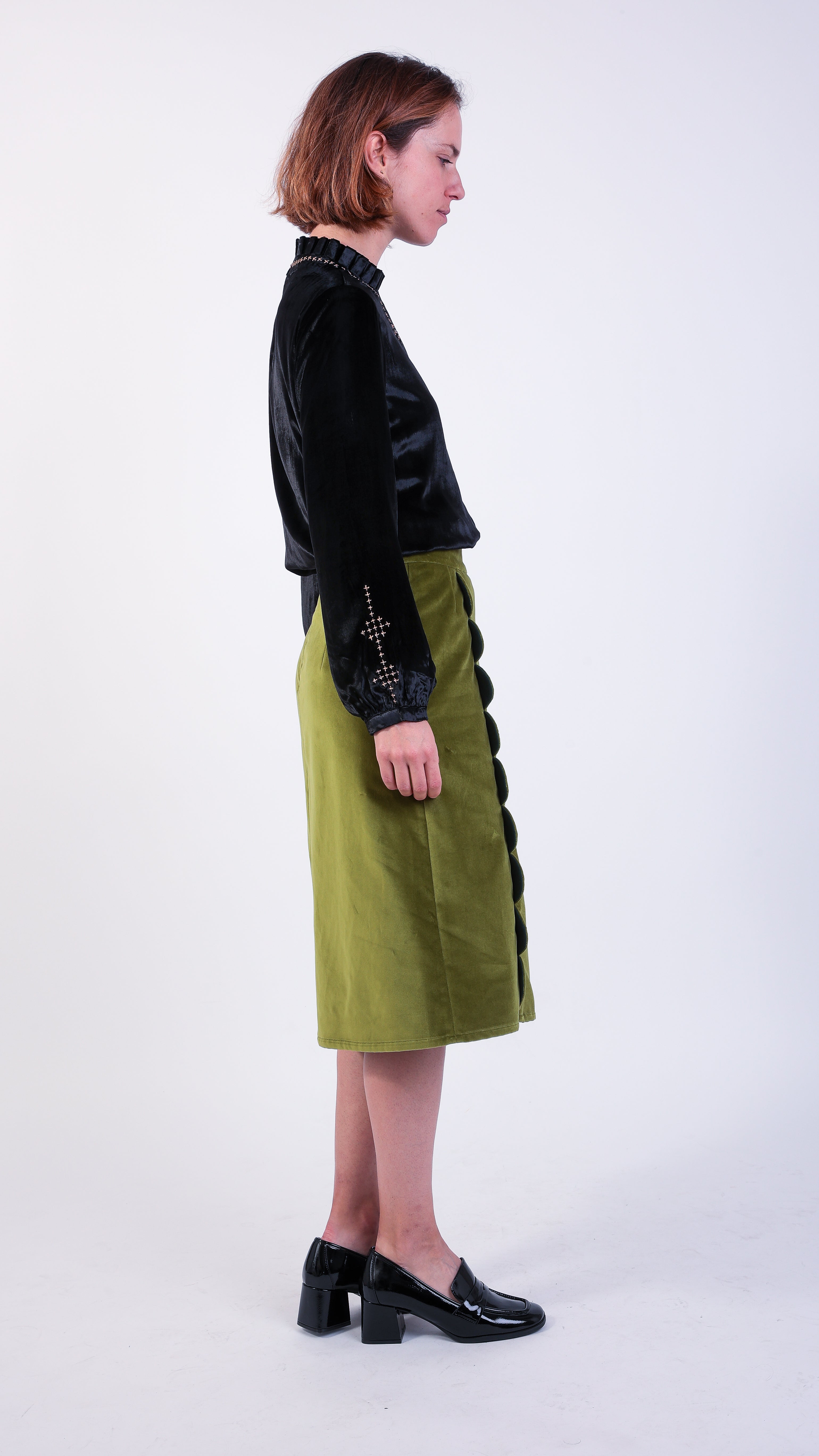 Woman wearing scallop detail green velvet skirt