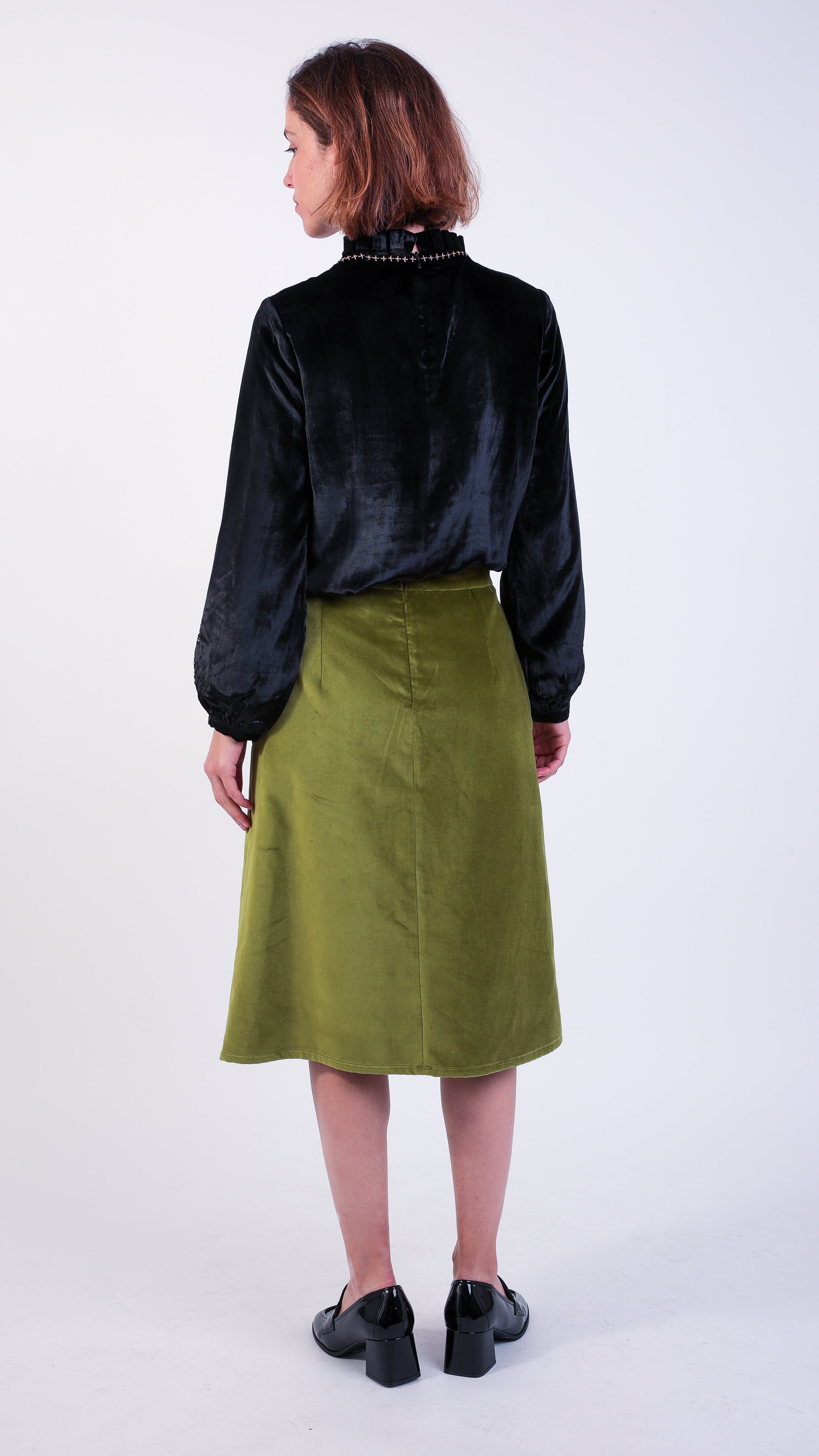 Woman wearing scallop detail green velvet skirt