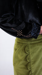 Woman wearing scallop detail green velvet skirt