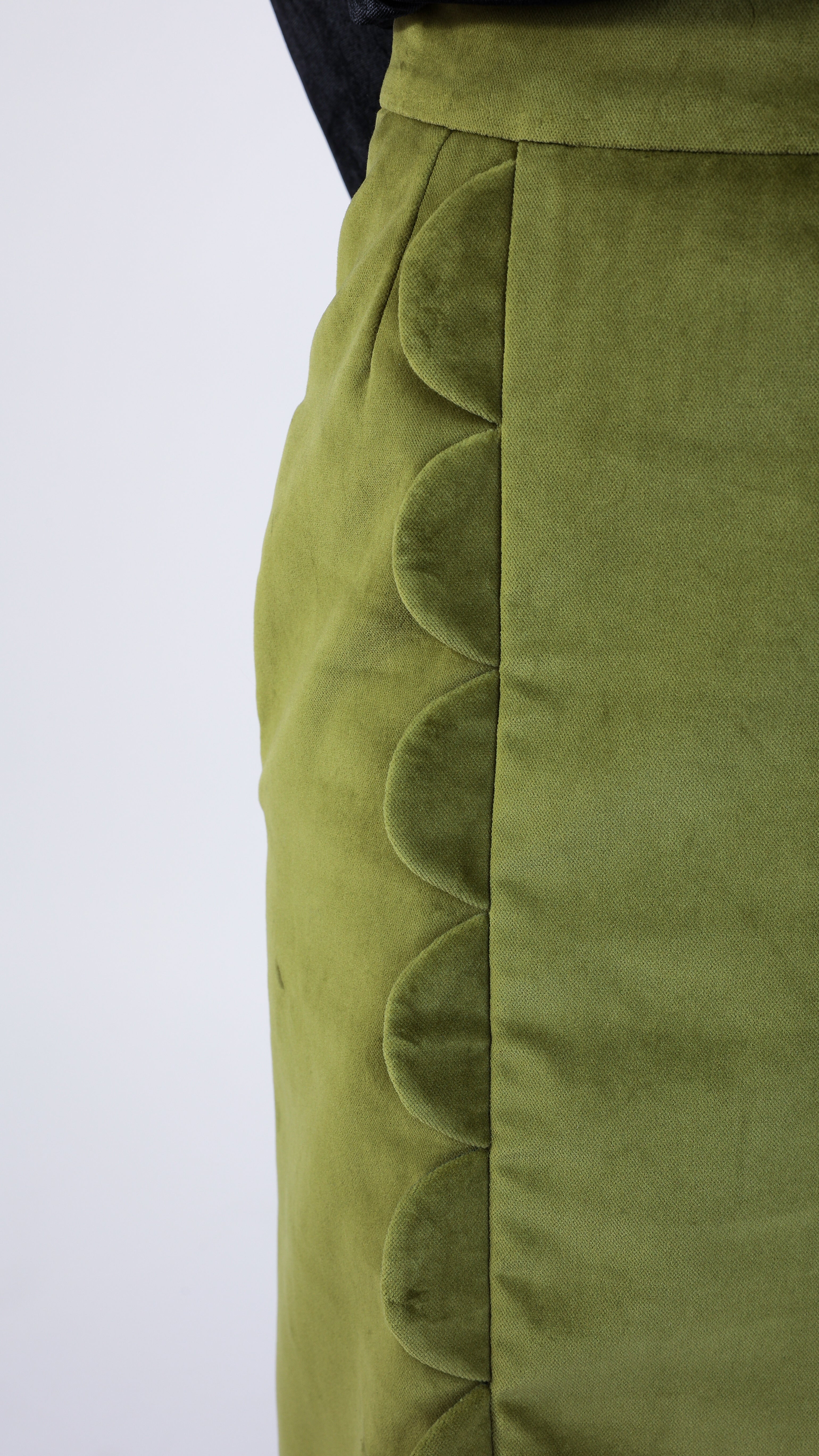 Woman wearing scallop detail green velvet skirt