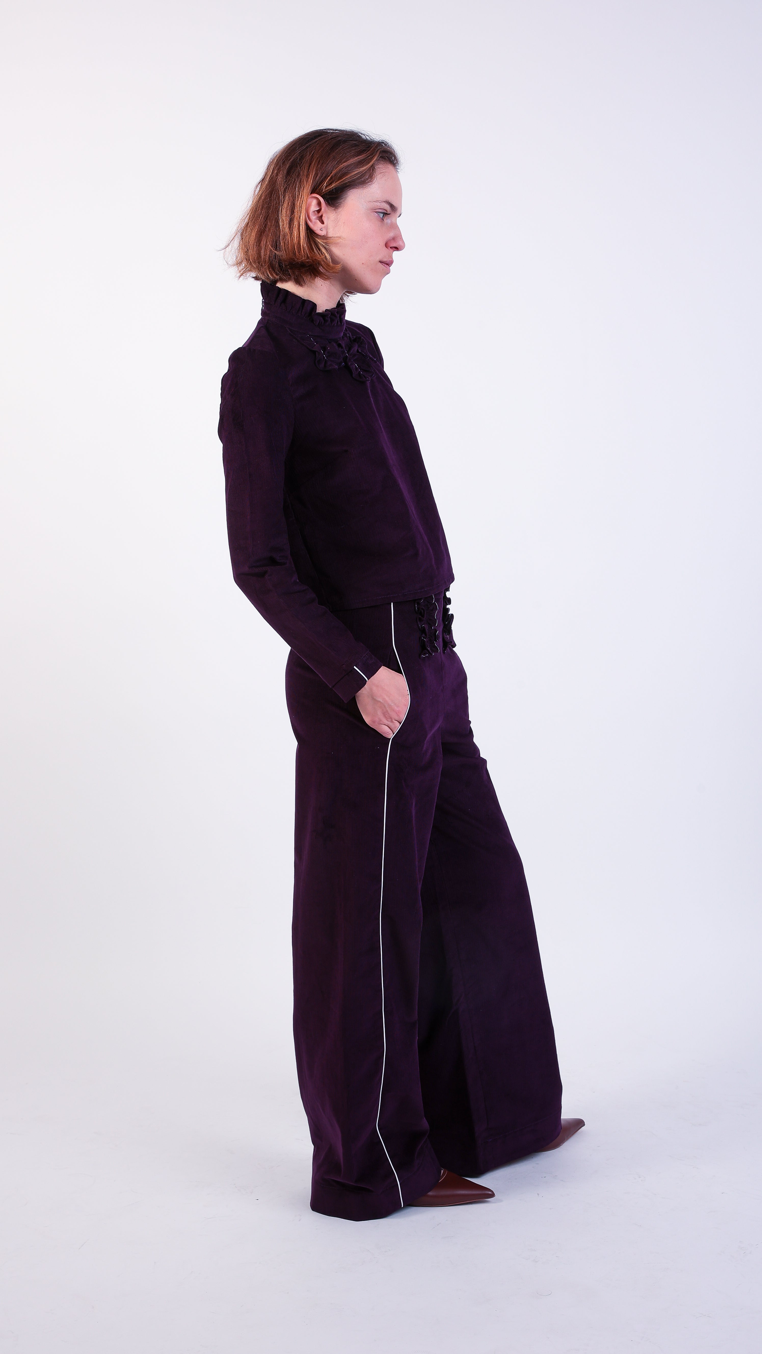 woman wearing VAAI aubergine corduroy high waisted ruffle trousers 