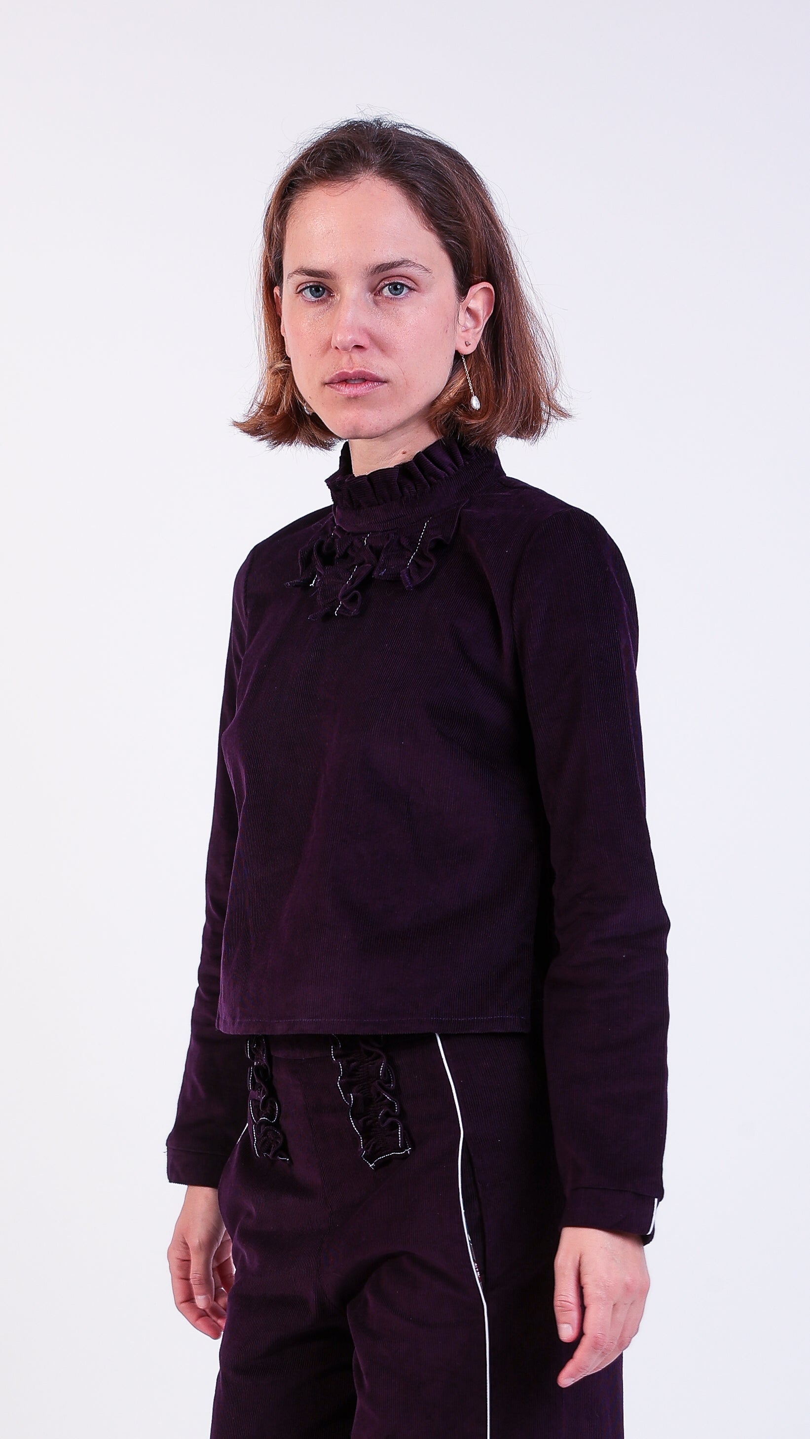 woman wearing VAAI aubergine corduroy ruffle top