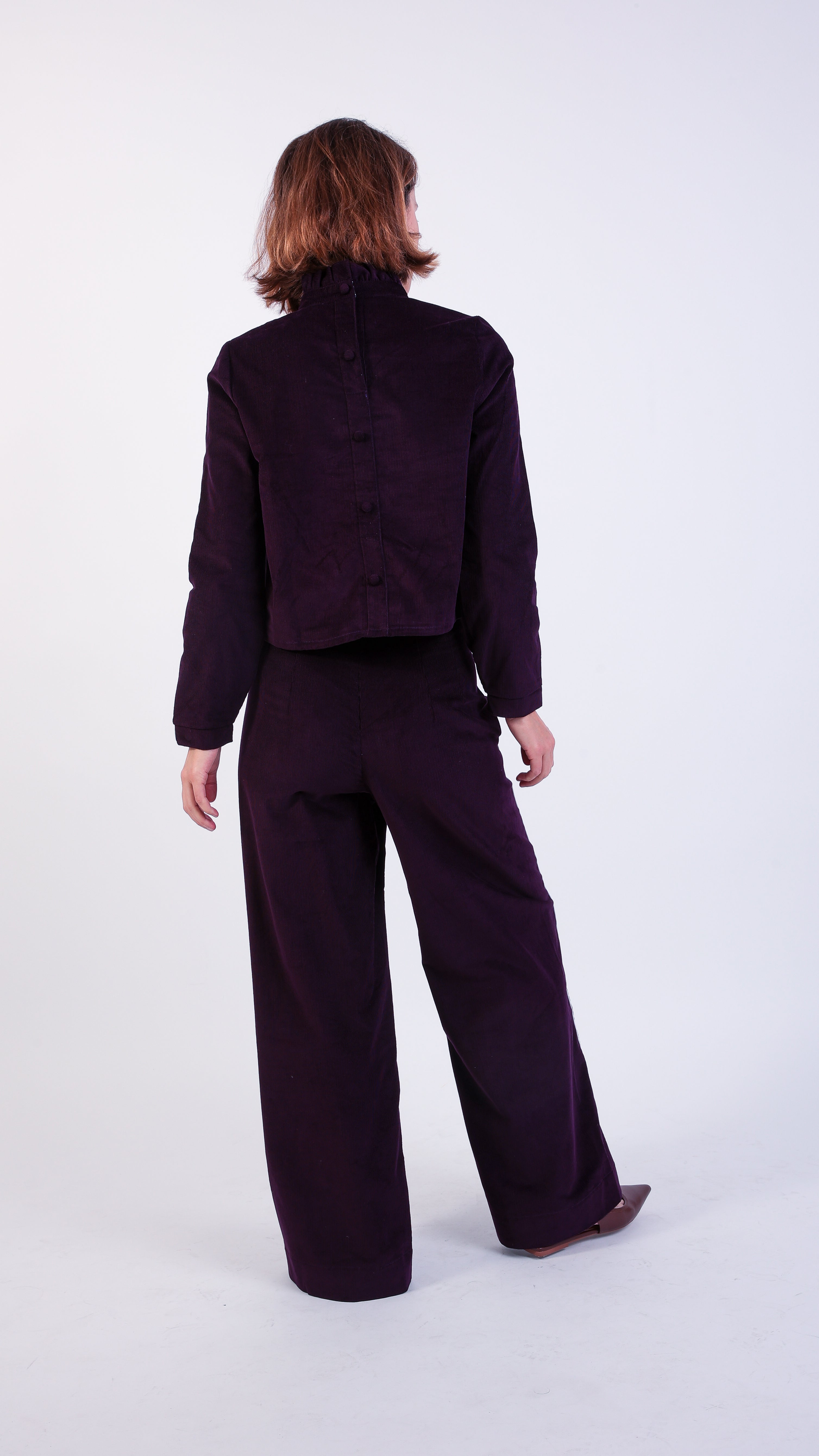 woman wearing VAAI aubergine corduroy high waisted ruffle trousers 